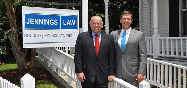 Photo of the firm's attorneys standing next to the sign outside their office